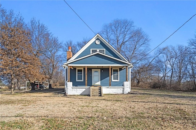 view of front of property featuring a front yard, a porch, and a chimney