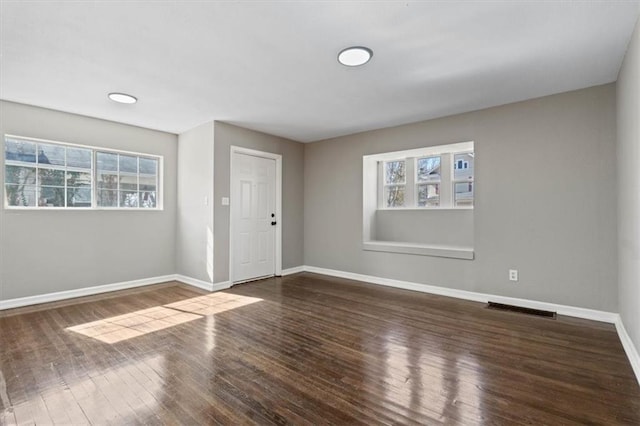 empty room with visible vents, baseboards, and wood finished floors