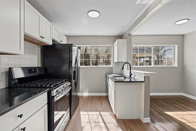 kitchen featuring gas stove, baseboards, a sink, and light wood finished floors