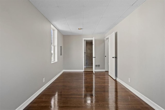 spare room featuring a drop ceiling, wood finished floors, visible vents, and baseboards