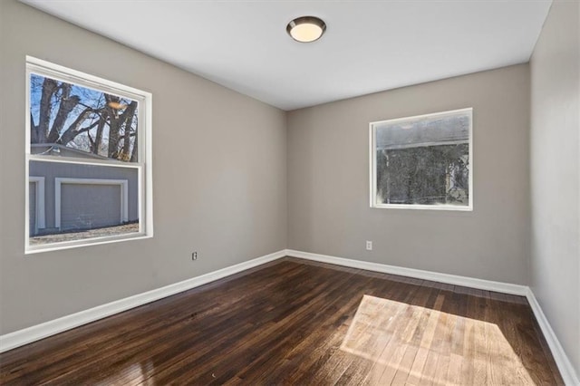 spare room with dark wood finished floors and baseboards