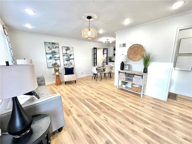 living room featuring ornamental molding, visible vents, light wood-style flooring, and baseboards