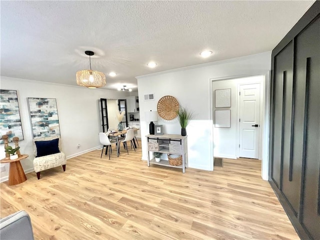 living area with a textured ceiling, crown molding, visible vents, and light wood-style floors