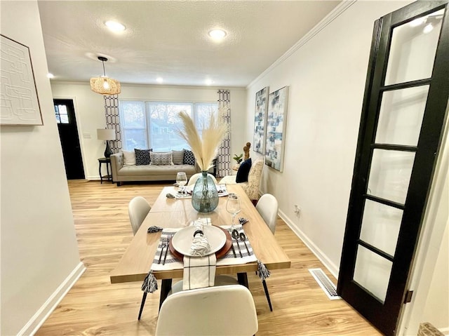 dining space with baseboards, visible vents, ornamental molding, wood finished floors, and a textured ceiling