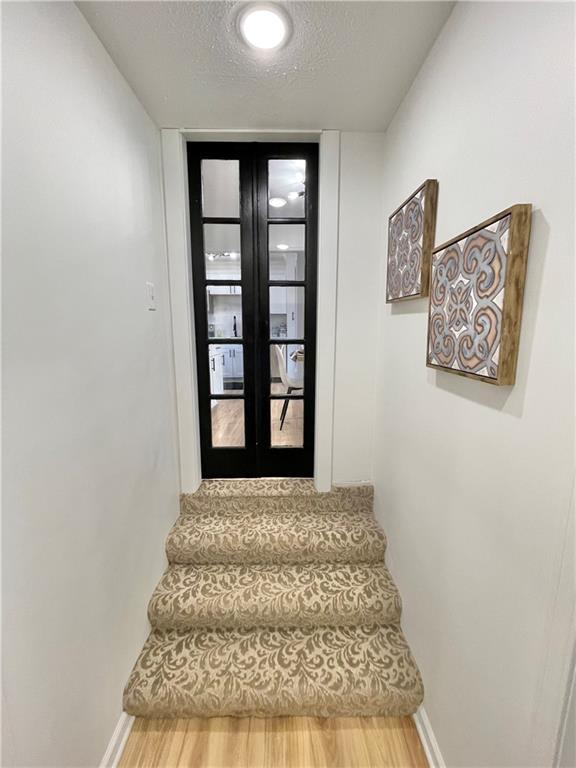 stairway featuring a textured ceiling, baseboards, and wood finished floors