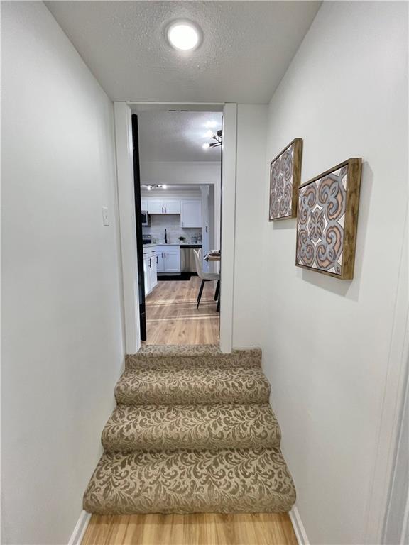 stairway with a textured ceiling, baseboards, and wood finished floors