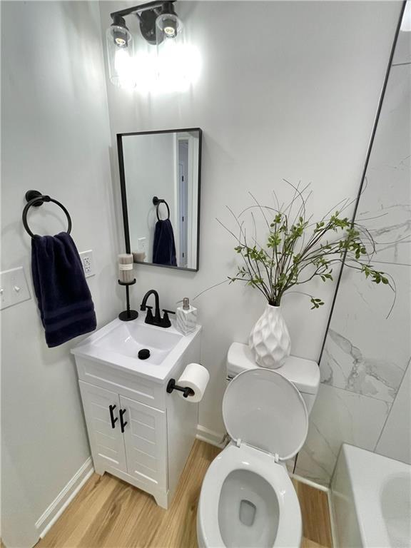 full bath featuring vanity, wood finished floors, toilet, and baseboards