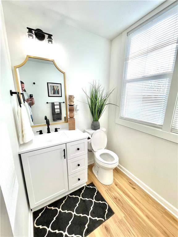 bathroom with toilet, baseboards, wood finished floors, and vanity