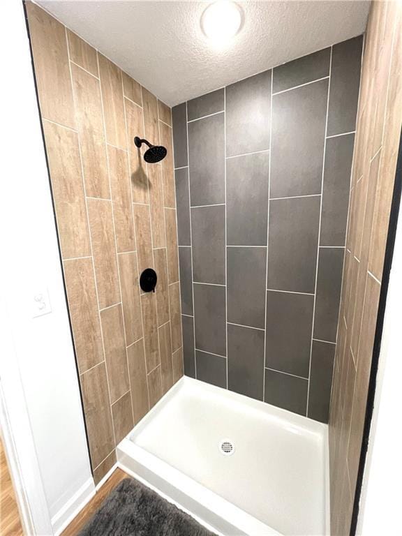 bathroom featuring tiled shower and a textured ceiling