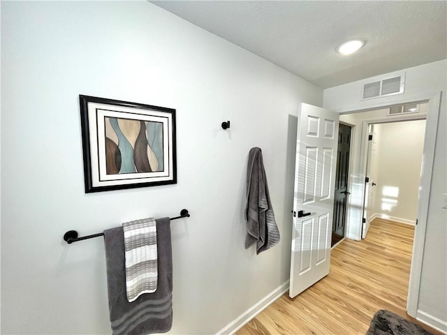 bathroom with wood finished floors, visible vents, and baseboards