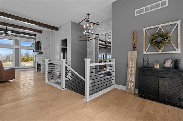 interior space featuring beam ceiling, a fireplace, wood finished floors, and visible vents