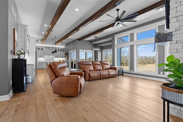 living area with light wood finished floors, a notable chandelier, beam ceiling, and recessed lighting