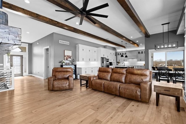 living area with beam ceiling, recessed lighting, visible vents, light wood-type flooring, and baseboards