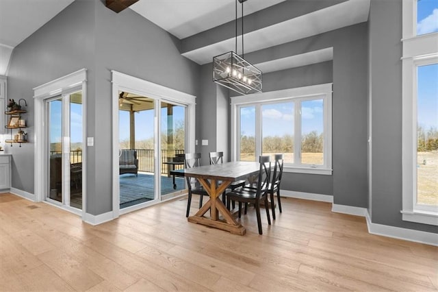 dining space with light wood-type flooring, baseboards, and a notable chandelier