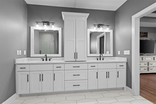 bathroom with double vanity, baseboards, and a sink