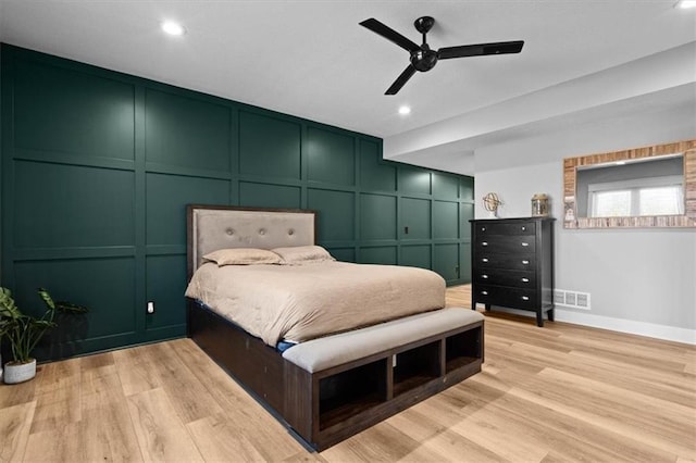 bedroom featuring light wood-style floors, recessed lighting, visible vents, and a decorative wall