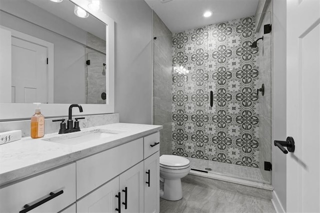 bathroom with toilet, a stall shower, and vanity