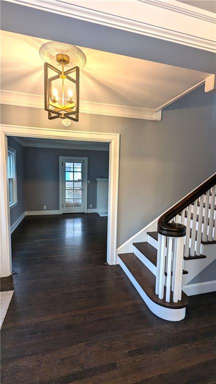 stairs featuring baseboards, ornamental molding, wood finished floors, and a notable chandelier