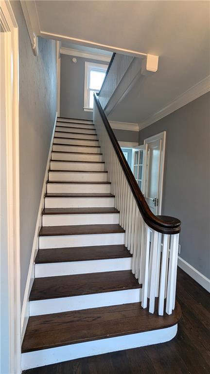 stairway with ornamental molding, hardwood / wood-style floors, and baseboards