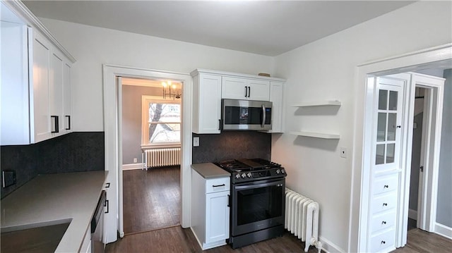 kitchen with dark wood-style floors, stainless steel appliances, white cabinetry, and radiator