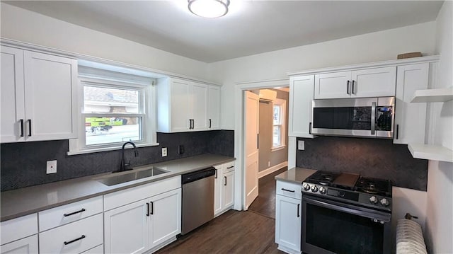 kitchen featuring decorative backsplash, appliances with stainless steel finishes, dark wood-type flooring, white cabinetry, and a sink