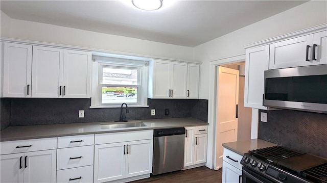 kitchen with stainless steel appliances, decorative backsplash, a sink, and white cabinets