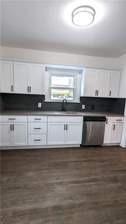 kitchen with a sink, white cabinetry, stainless steel dishwasher, decorative backsplash, and dark wood finished floors