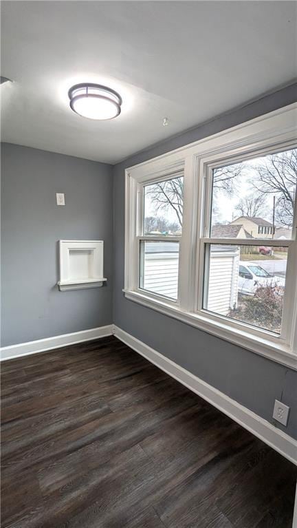 spare room featuring dark wood-style floors and baseboards