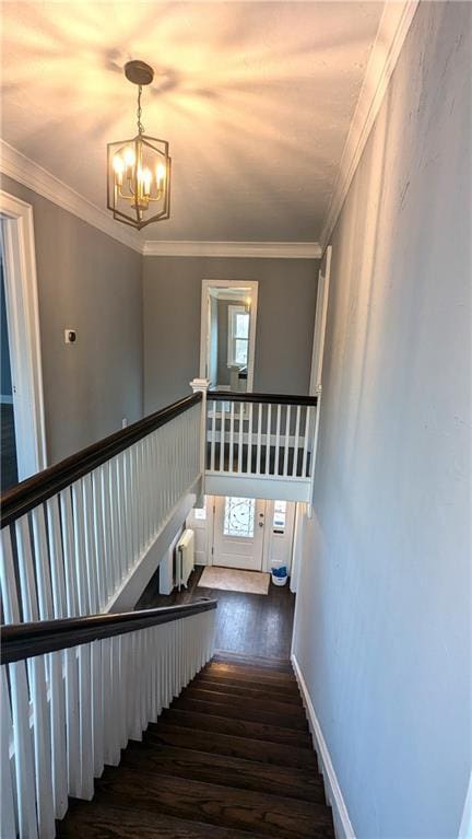 stairway with baseboards, crown molding, an inviting chandelier, and wood finished floors