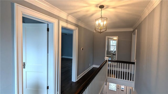 hall with a notable chandelier, baseboards, crown molding, and an upstairs landing