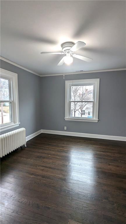 unfurnished room with ornamental molding, baseboards, dark wood finished floors, and radiator heating unit