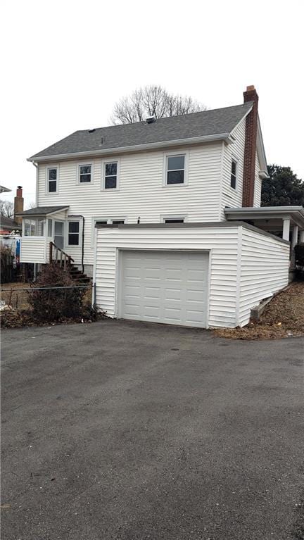 view of front facade with a garage, driveway, and a chimney