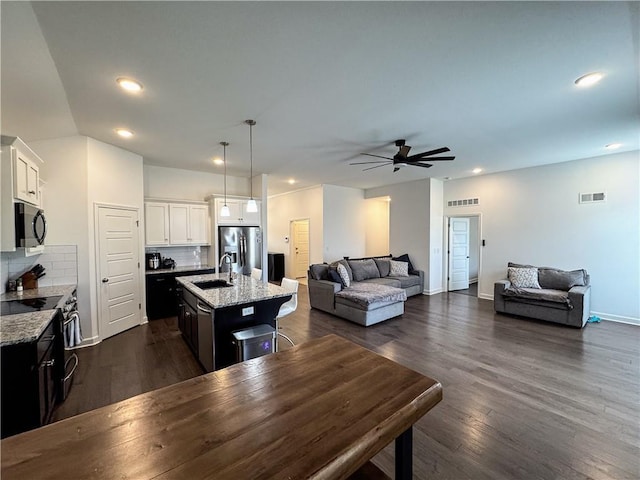 kitchen with dark wood-style floors, stainless steel appliances, visible vents, open floor plan, and a sink