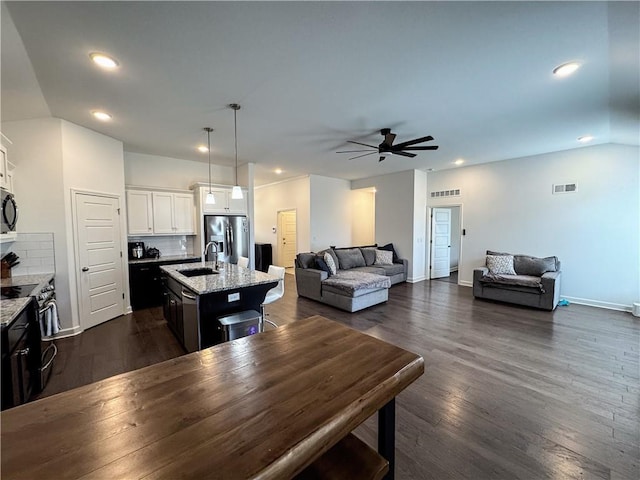 kitchen with visible vents, open floor plan, dark wood-style flooring, stainless steel appliances, and a sink