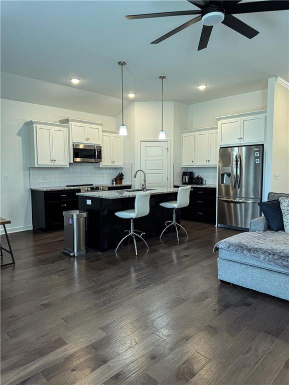 kitchen with stainless steel appliances, a kitchen island with sink, and dark wood finished floors