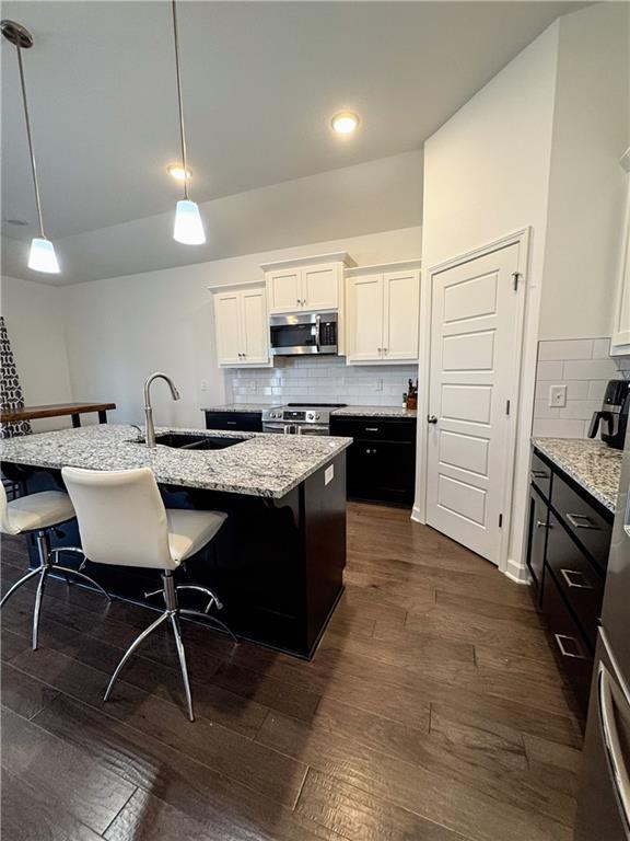 kitchen featuring dark wood-style floors, stainless steel appliances, a breakfast bar area, and a sink