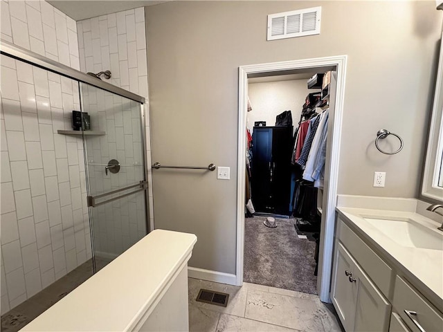 full bath featuring a stall shower, visible vents, a walk in closet, and vanity