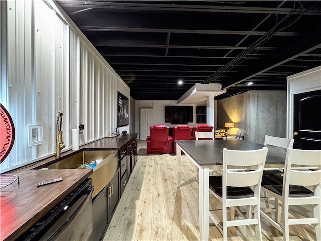 kitchen with dark countertops, dishwasher, light wood finished floors, and a sink