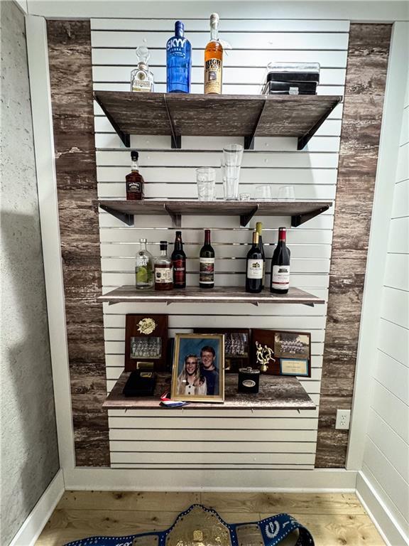 bar featuring a dry bar, baseboards, and wood finished floors