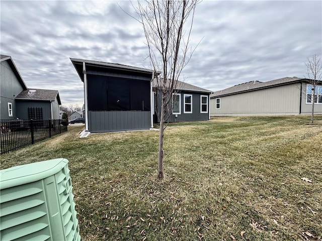 back of house with a lawn, fence, and a sunroom