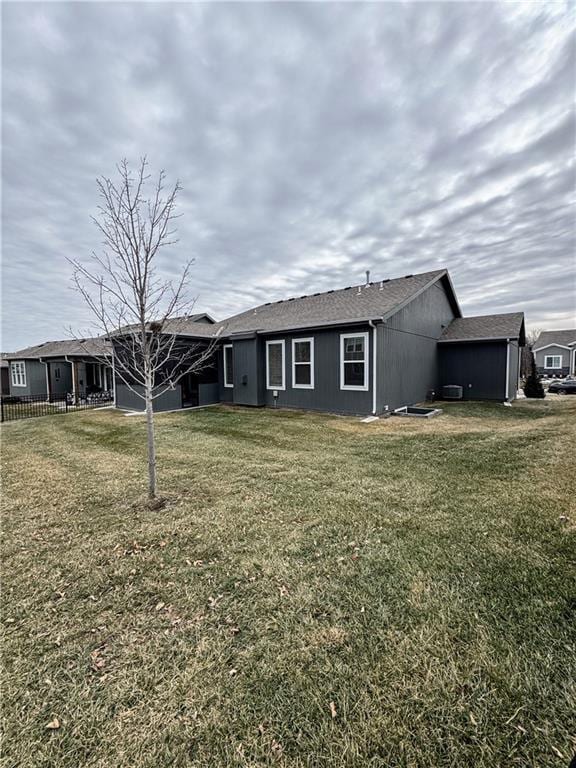 rear view of house featuring fence and a lawn