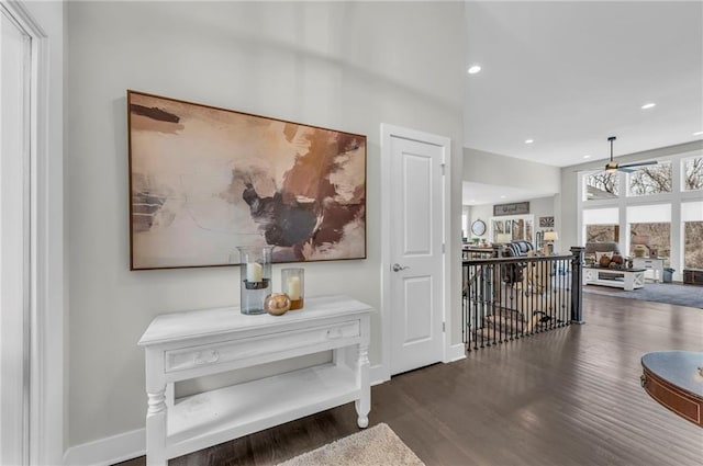 hallway with baseboards, wood finished floors, an upstairs landing, and recessed lighting