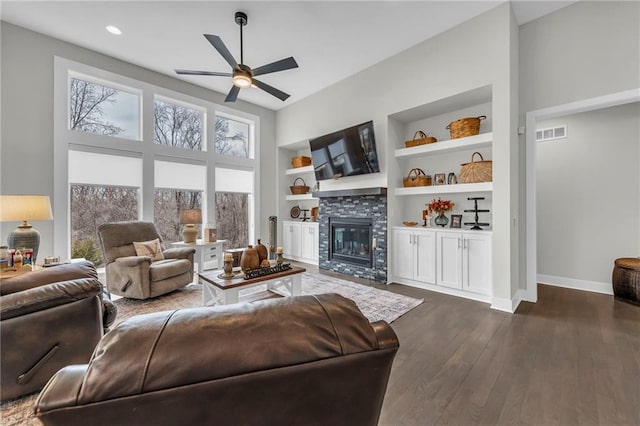 living room with built in features, dark wood finished floors, a fireplace, visible vents, and baseboards