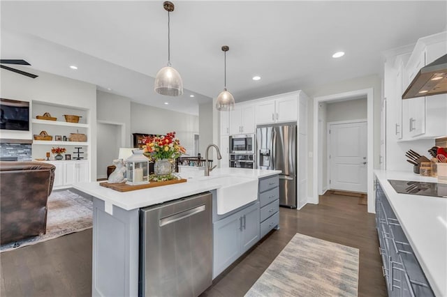 kitchen featuring white cabinets, appliances with stainless steel finishes, open floor plan, light countertops, and a sink