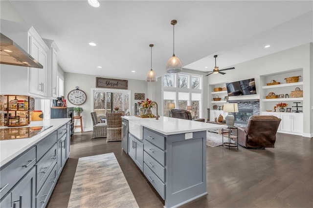 kitchen with white cabinets, wall chimney exhaust hood, light countertops, gray cabinetry, and a fireplace