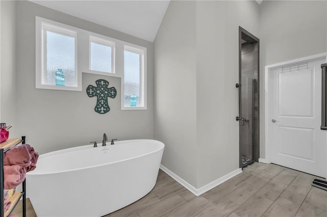 bathroom featuring a stall shower, wood finish floors, vaulted ceiling, and a soaking tub