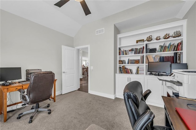 carpeted home office with lofted ceiling, ceiling fan, visible vents, and baseboards