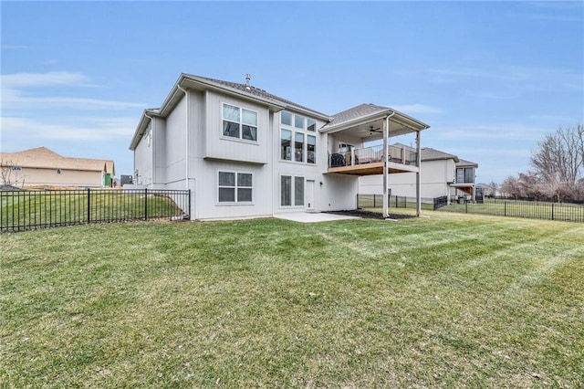 rear view of property with a fenced backyard, a balcony, a ceiling fan, a lawn, and a patio area