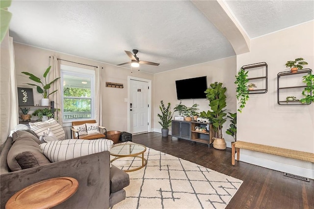 living room featuring a textured ceiling, ceiling fan, wood finished floors, visible vents, and baseboards