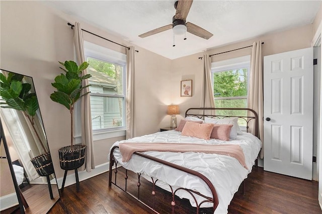 bedroom with multiple windows, wood finished floors, and baseboards